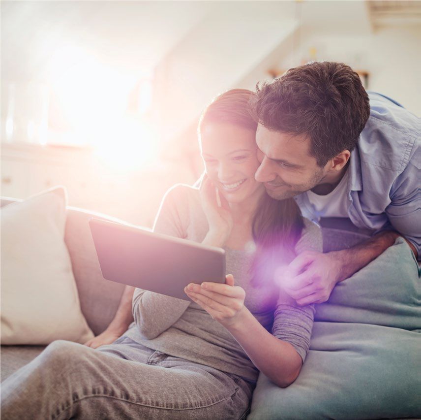 Man and woman sitting on a couch looking at a tablet
